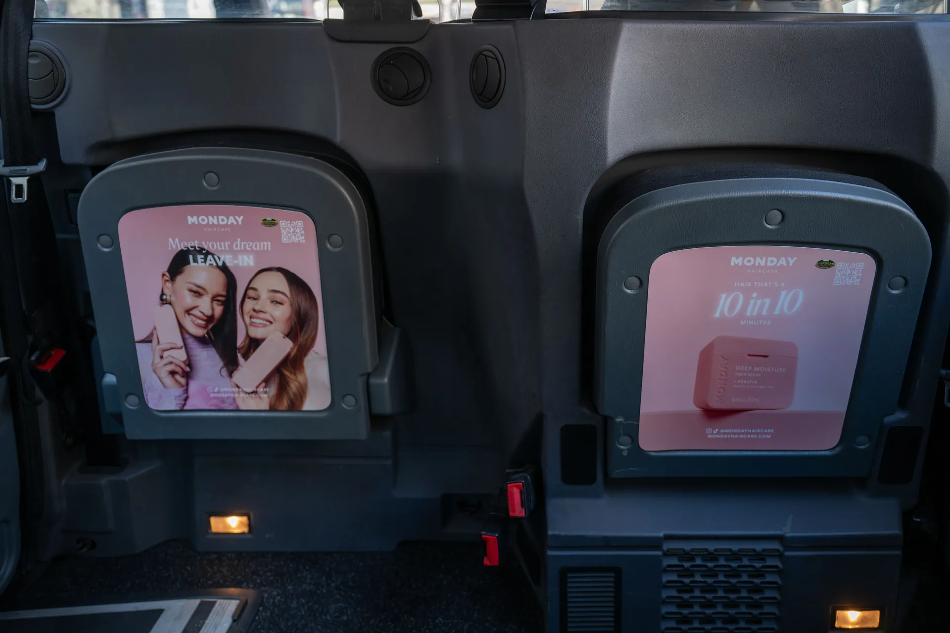Monday Haircare adverts on the two rear-facing tip seats inside a taxi