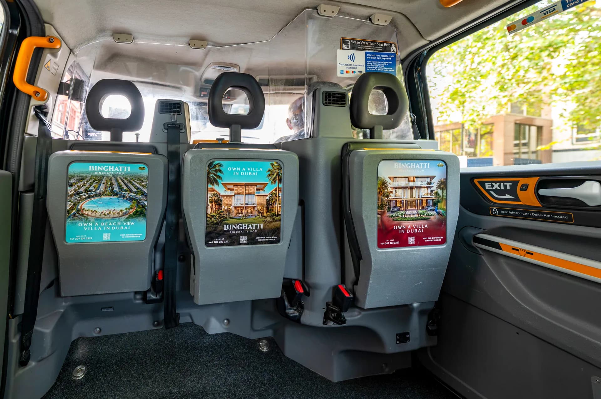 Three Binghatti adverts on the rear-facing tip seats inside a taxi