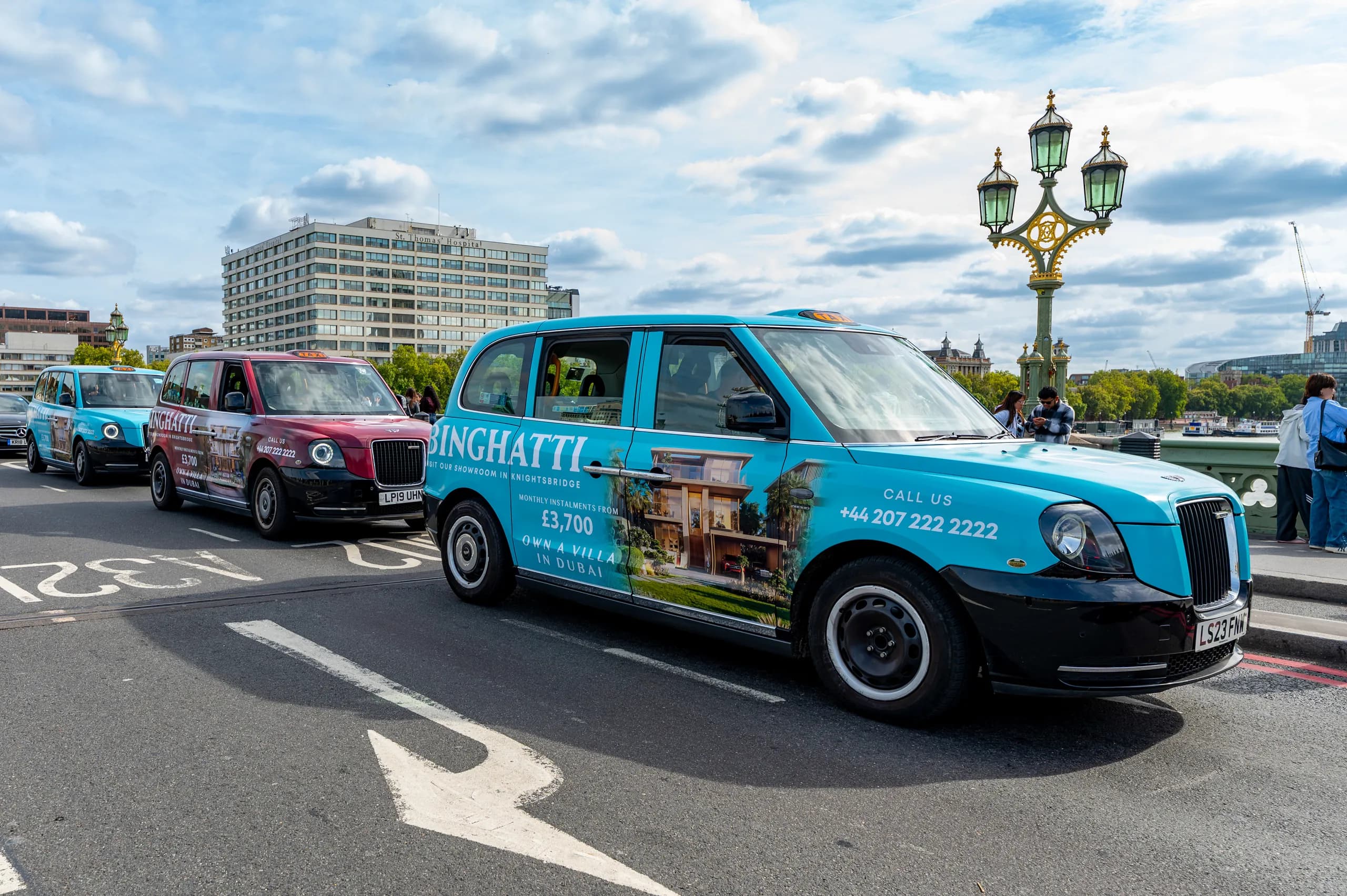 Taxi in turquoise Binghatti livery crossing Westminster Bridge, with two more liveried taxis behind