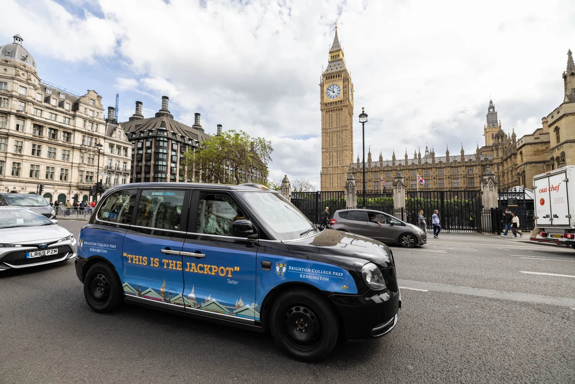 Taxi with blue Brighton College Prep advertising on a city street