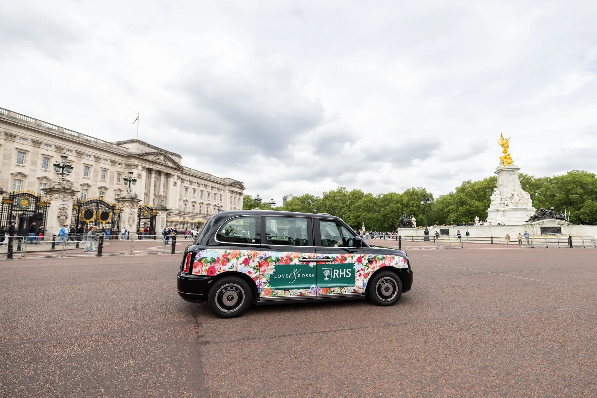 Black taxi with RHS floral livery, a palace building behind
