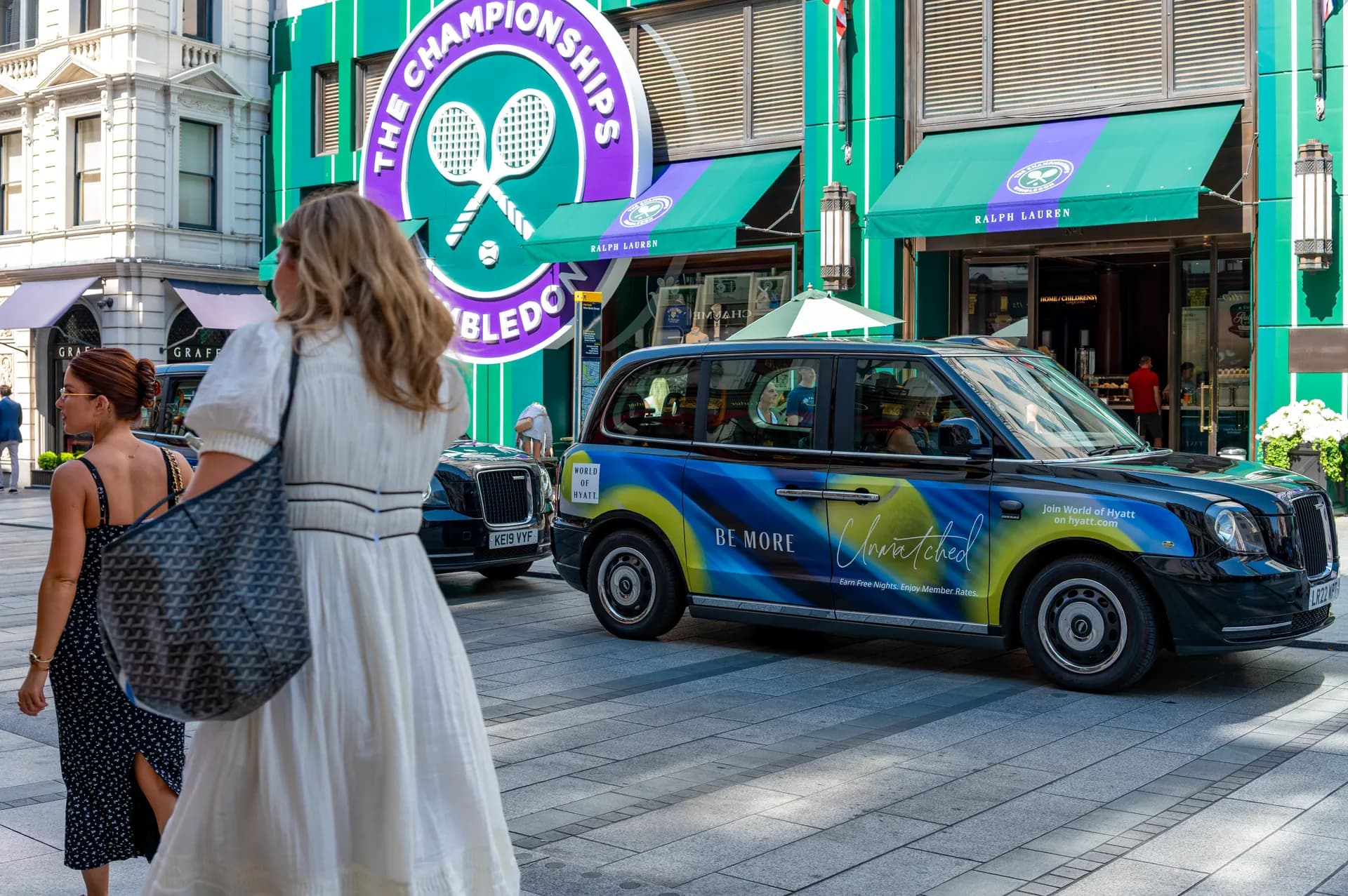Taxi with World of Hyatt advertising on Bond Street, a pedestrian in the foreground